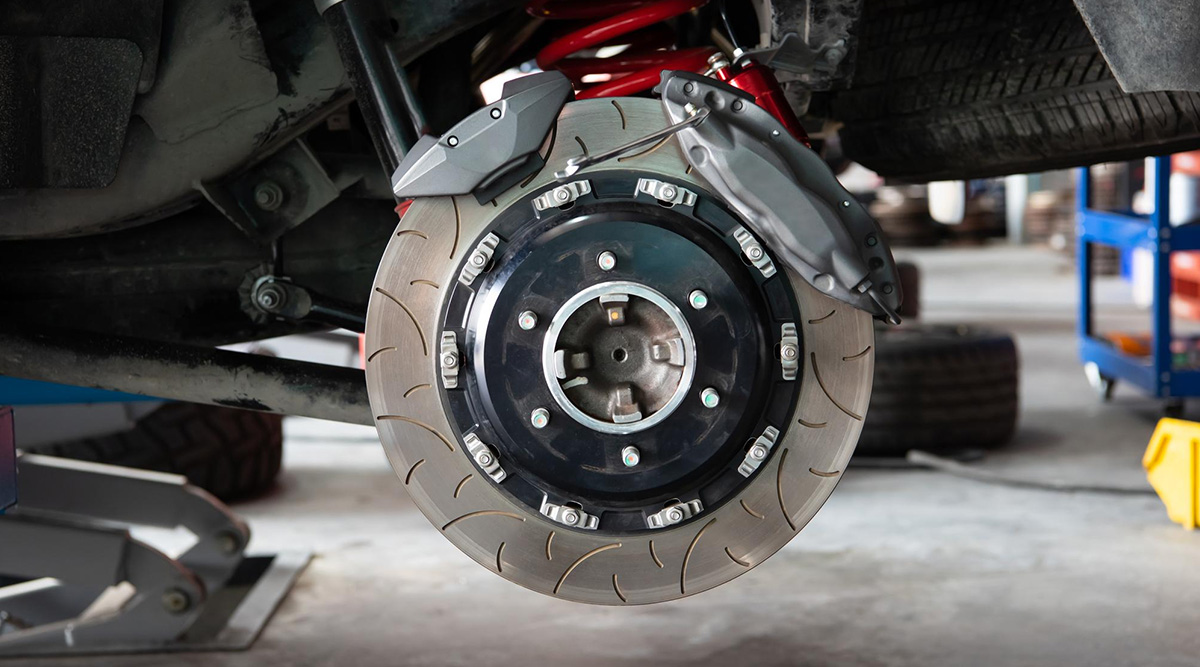 Exposed brake system, including pads and rotor disc, on a car in a repair garage.